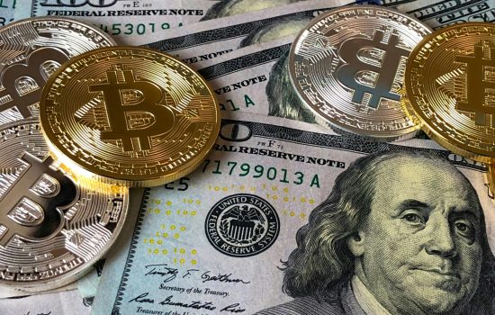 A close-up photo depicting Bitcoin coins on top of US dollar bills, symbolizing finance and cryptocurrency.